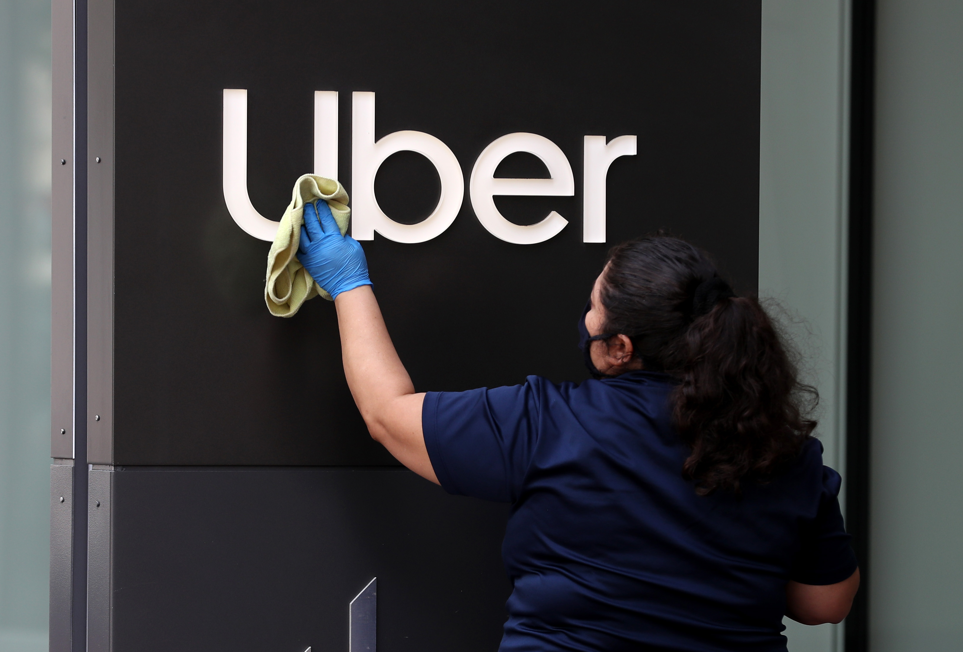 A worker cleans a sign in front of the Uber headquarters in San Francisco in May.&nbsp;