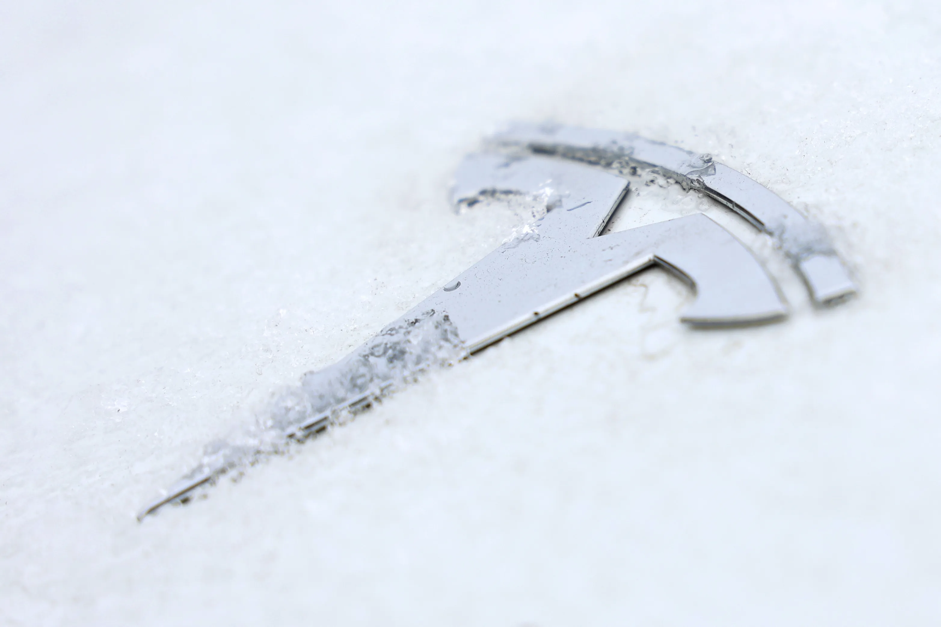 Frost on the badge of a Tesla Model Y electric vehicle.