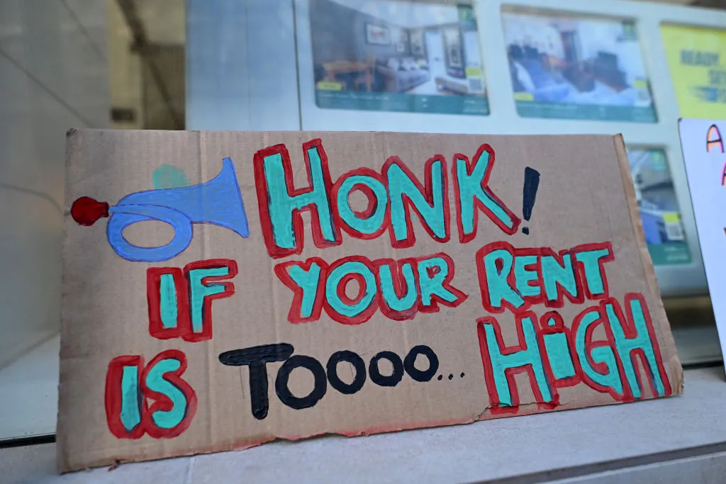 Protesters' placards are pictured in the window of a Foxtons estate agents' demonstrate outside in central London in 2024.