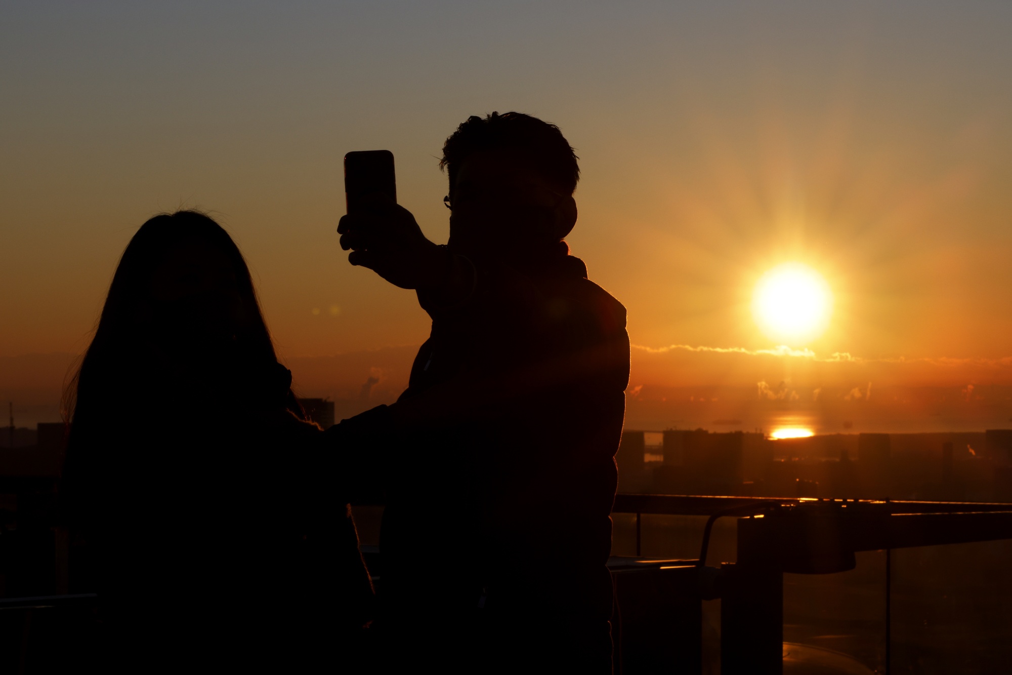 Visitors take a selfie photograph while the sun rises, seen from the Shibuya Sky observation deck at the Shibuya Scramble Square building in Tokyo, Japan, on Sunday, Jan. 1, 2023.