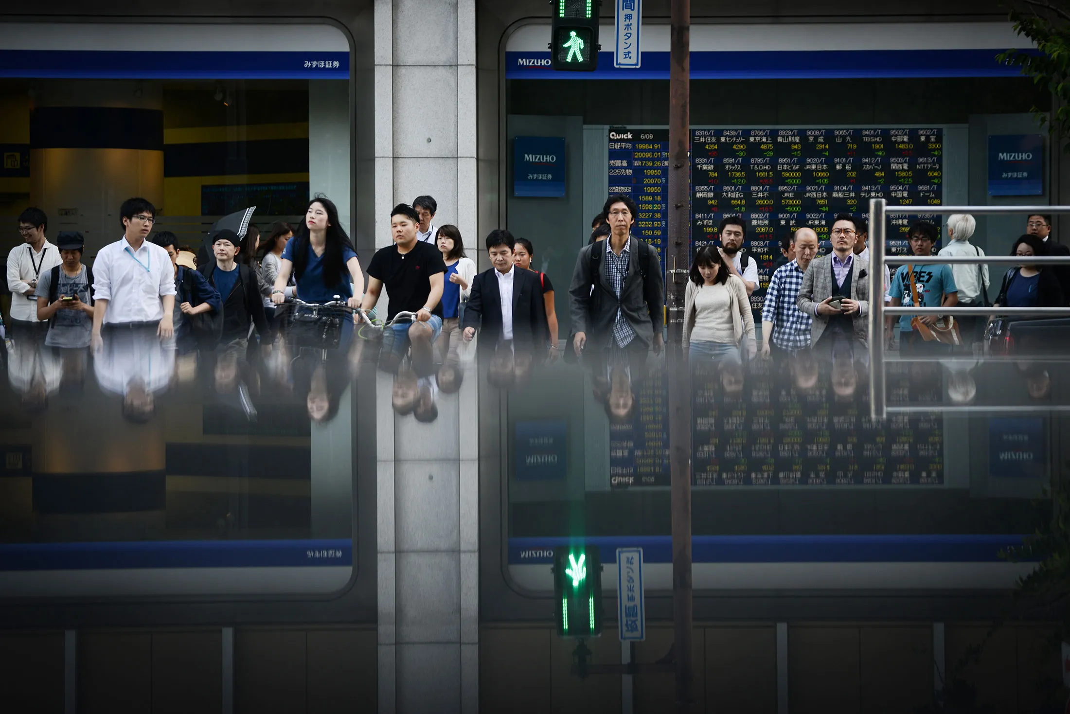 Pedestrians cross a road in front of an electronic stock board outside a securities firm in Tokyo, Japan, on Friday, June 9, 2017. The Topix index closed higher after swinging between gains and losses, and the yen weakened, as the market continued to digest former FBI chief James Comey's Senate testimony, the European Central Bank rate decision and U.K. election results.
