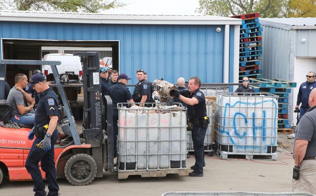 A Tulsa police officer sifting through a pile of seized cats