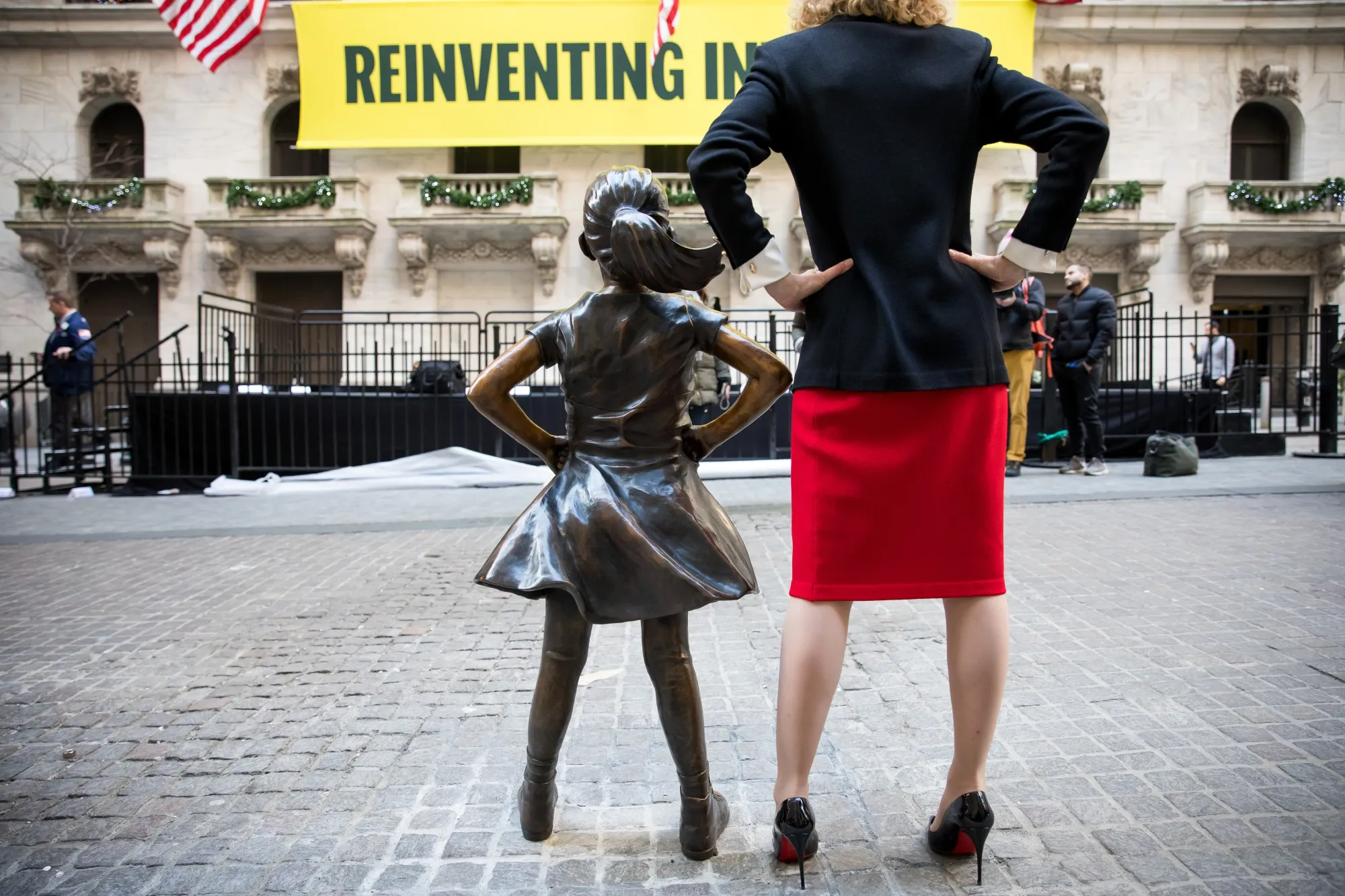 A person stands for a photograph with the "Fearless Girl" statue outside of the New York Stock Exchange.