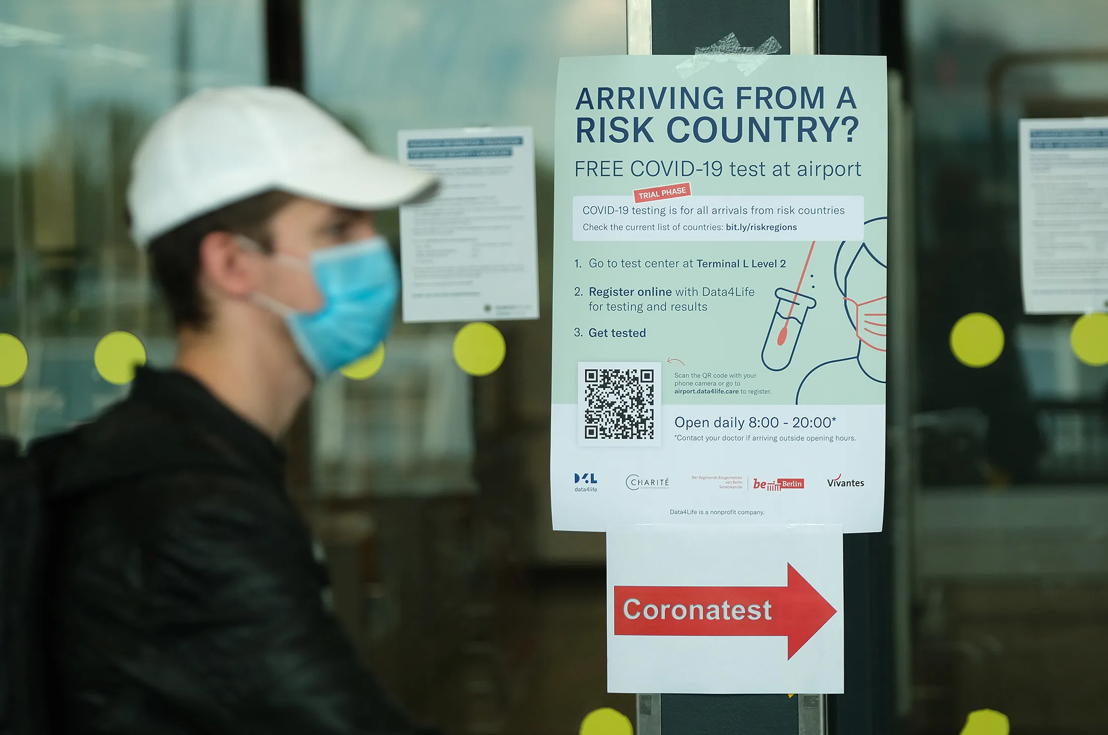 A man wearing a protective face masks walks past a sign directing travelers to a coronavirus testing station at Schoenefeld Airport on Aug. 4.&nbsp;
