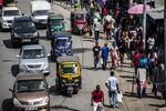 Automobiles and tuk-tuk drivers travel alongside pedestrians in Mombasa.