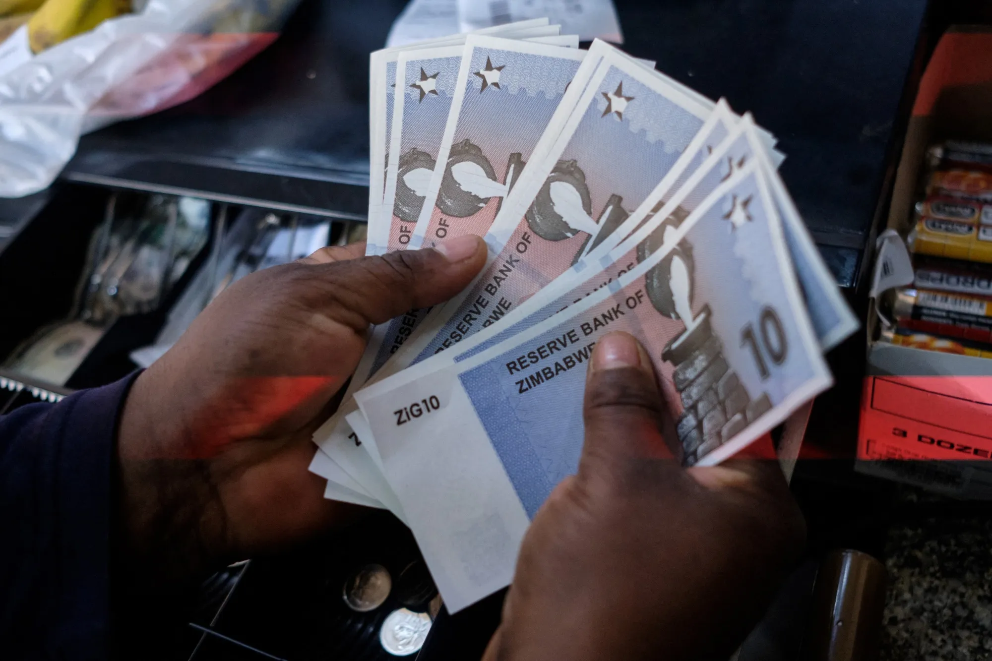 A cashier&nbsp;dispenses the new $10 ZiG, short for Zimbabwe Gold, banknote from a till as change in Harare on April 30.