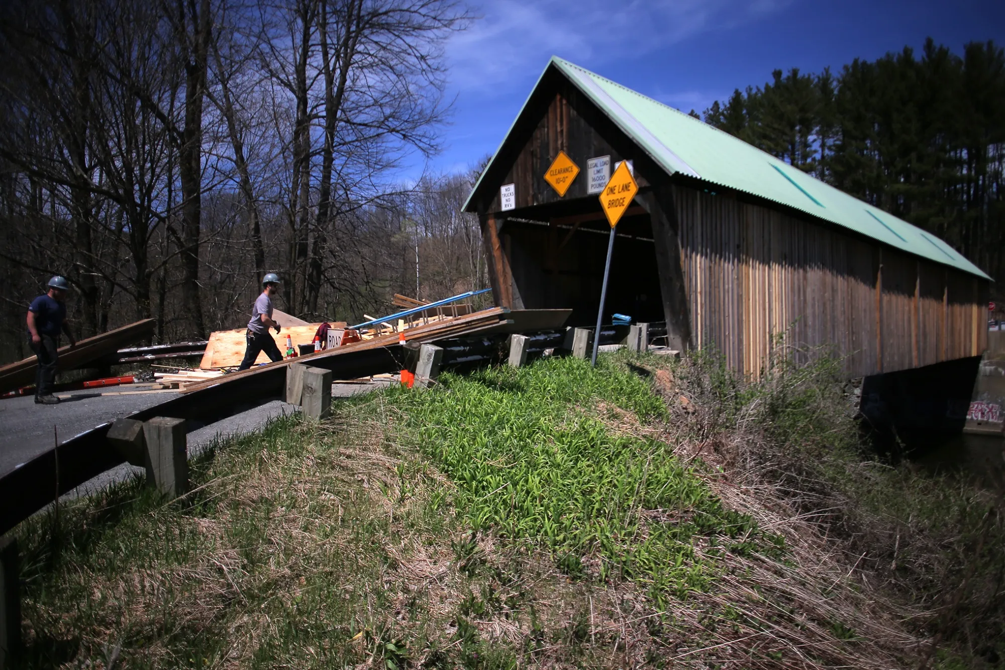 Workers remove construction materials after making repairs to the Lincoln Covered Bridge over the Ottauquechee River in Woodstock, Vermont.