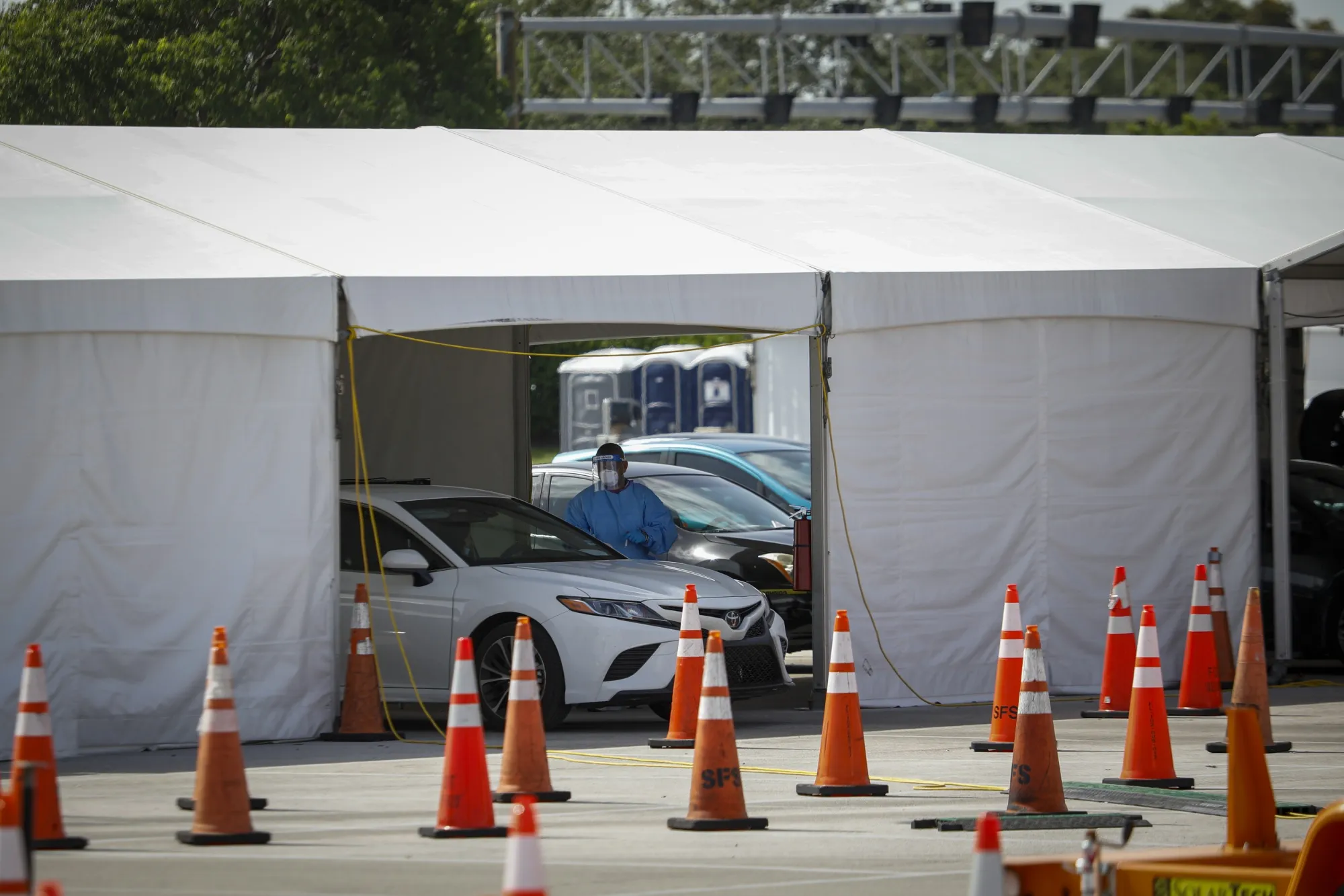 A medical worker wearing PPE assists a person at a Covid-19 drive-thru testing site in Miami Gardens, Florida.