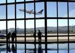 Airline passengers waiting for their flights watch from the terminal as a United Airlines airplane takes off at Phoenix Sky Harbor International Airport in Phoenix, Arizona.

