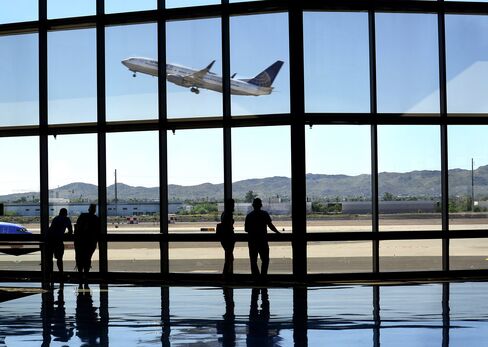 Airline passengers waiting for their flights watch from the terminal as a United Airlines airplane takes off at Phoenix Sky Harbor International Airport in Phoenix, Arizona.