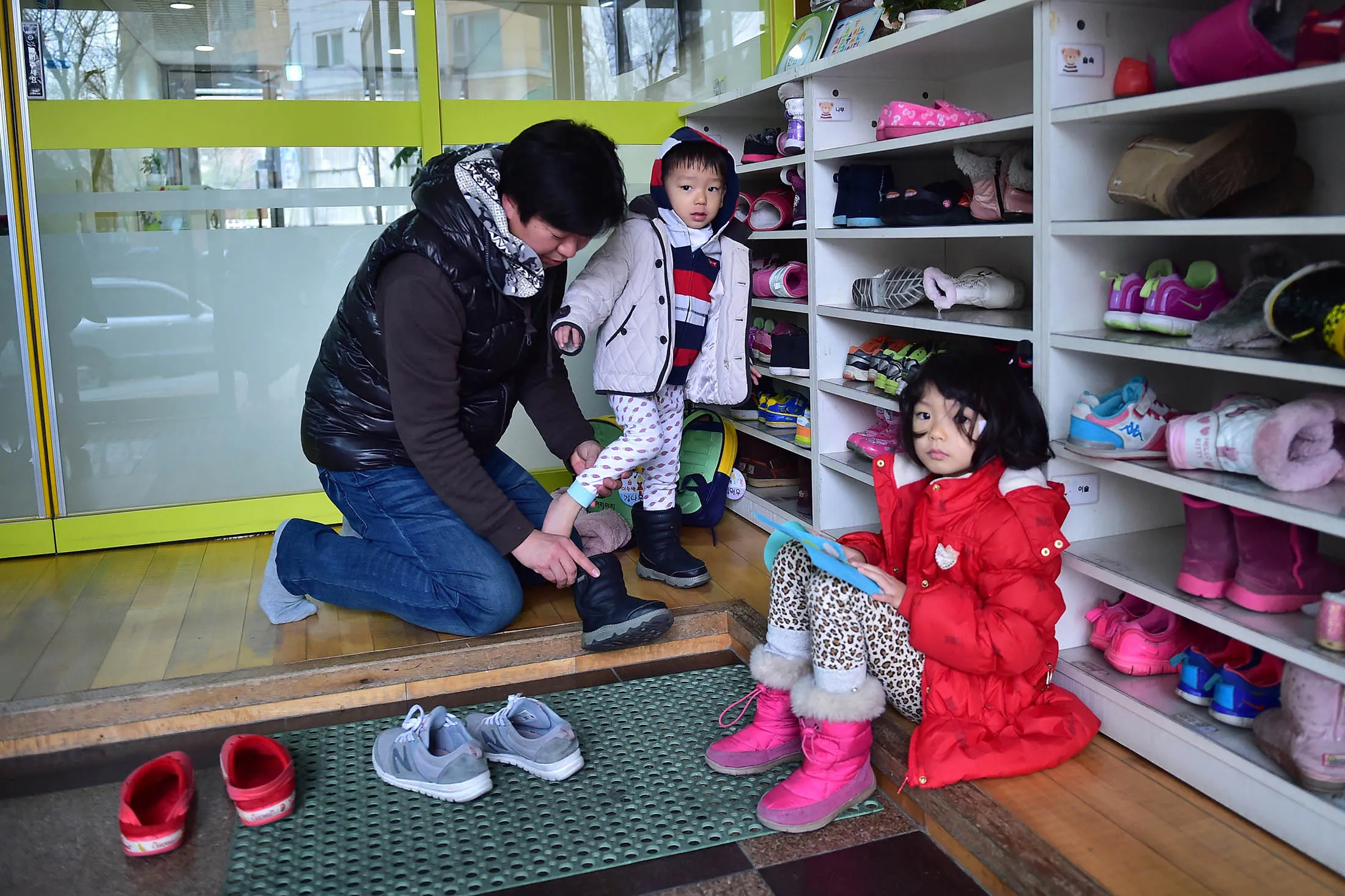 South Korean father Kim Jin-Sung puts footwear on his child at a child-care center in Seoul.
