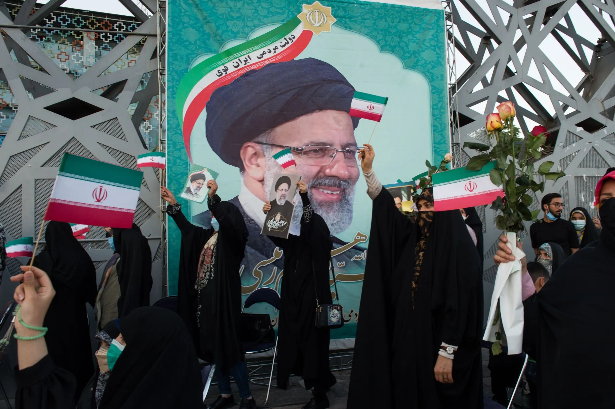 Supporters hold photographs of Ebrahim Raisi as they celebrate his presidential election win.