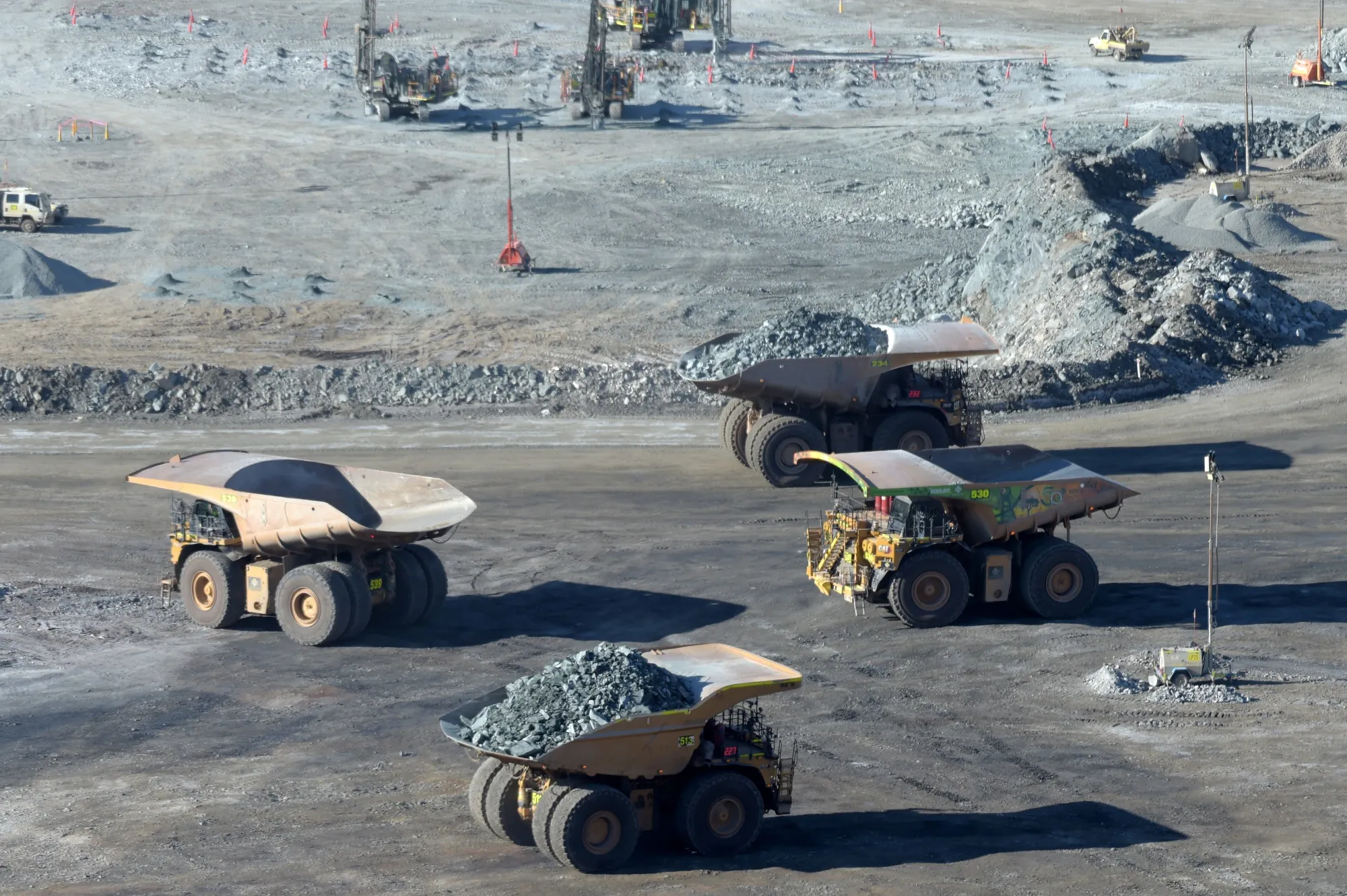 Haul trucks transport ore at an open pit gold mine.