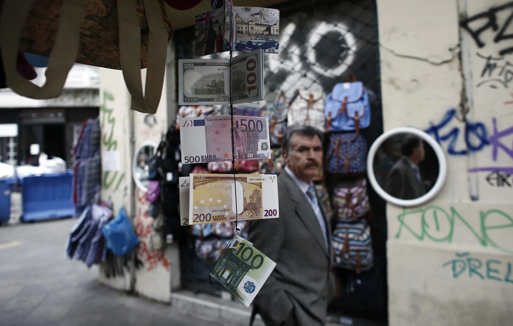 Wallets decorated with euro and US dollar banknote designs hang from a street vendor's store in Athens.
