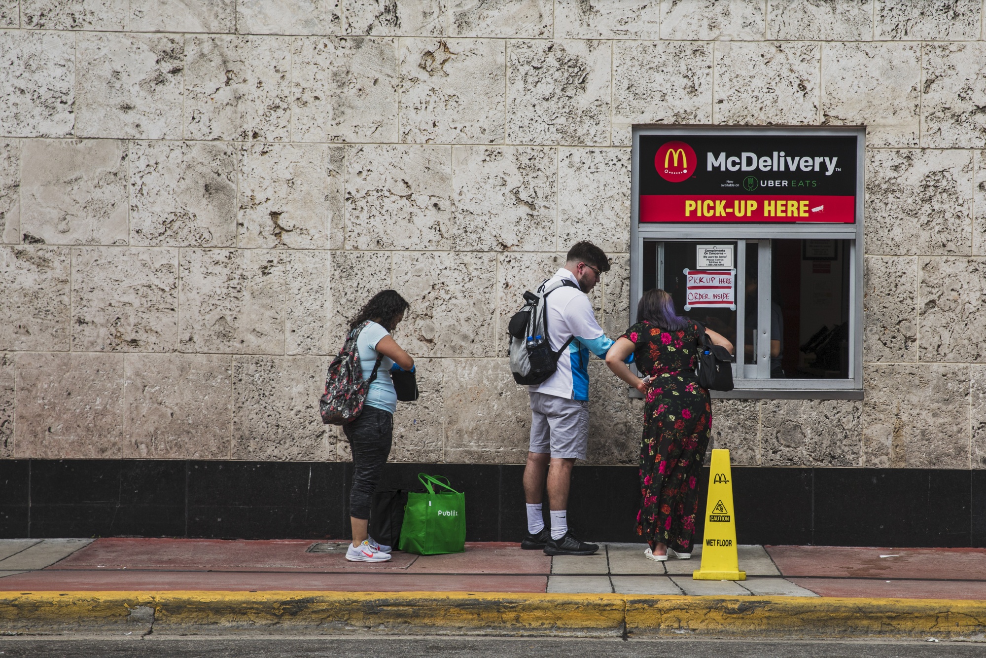 Customers stand outside a pick up window at a McDonald’s in Miami Beach.