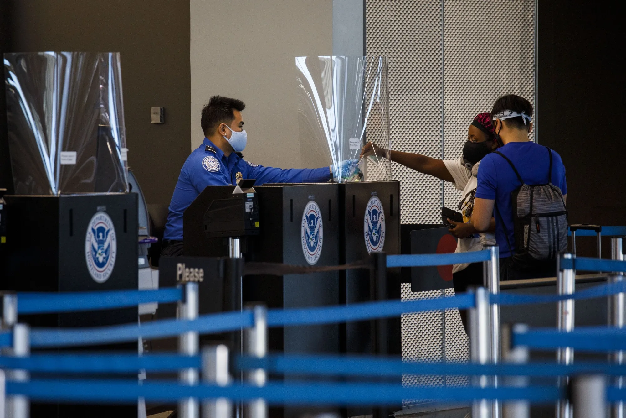 A TSA agent wearing a protective mask screens travelers at a checkpoint at O'Hare International Airport.