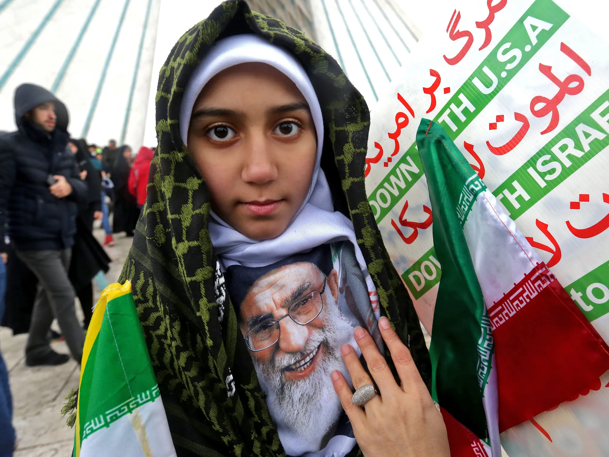 An Iranian girl poses with a potrait of Ayatollah Ali Khamenei.