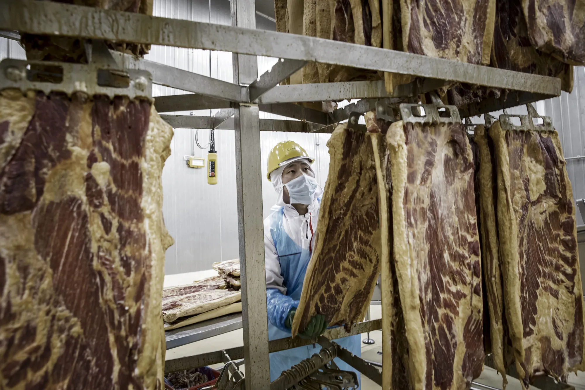 An employee handles imported&nbsp;pork belly on a production line&nbsp;in Zhengzhou, China.