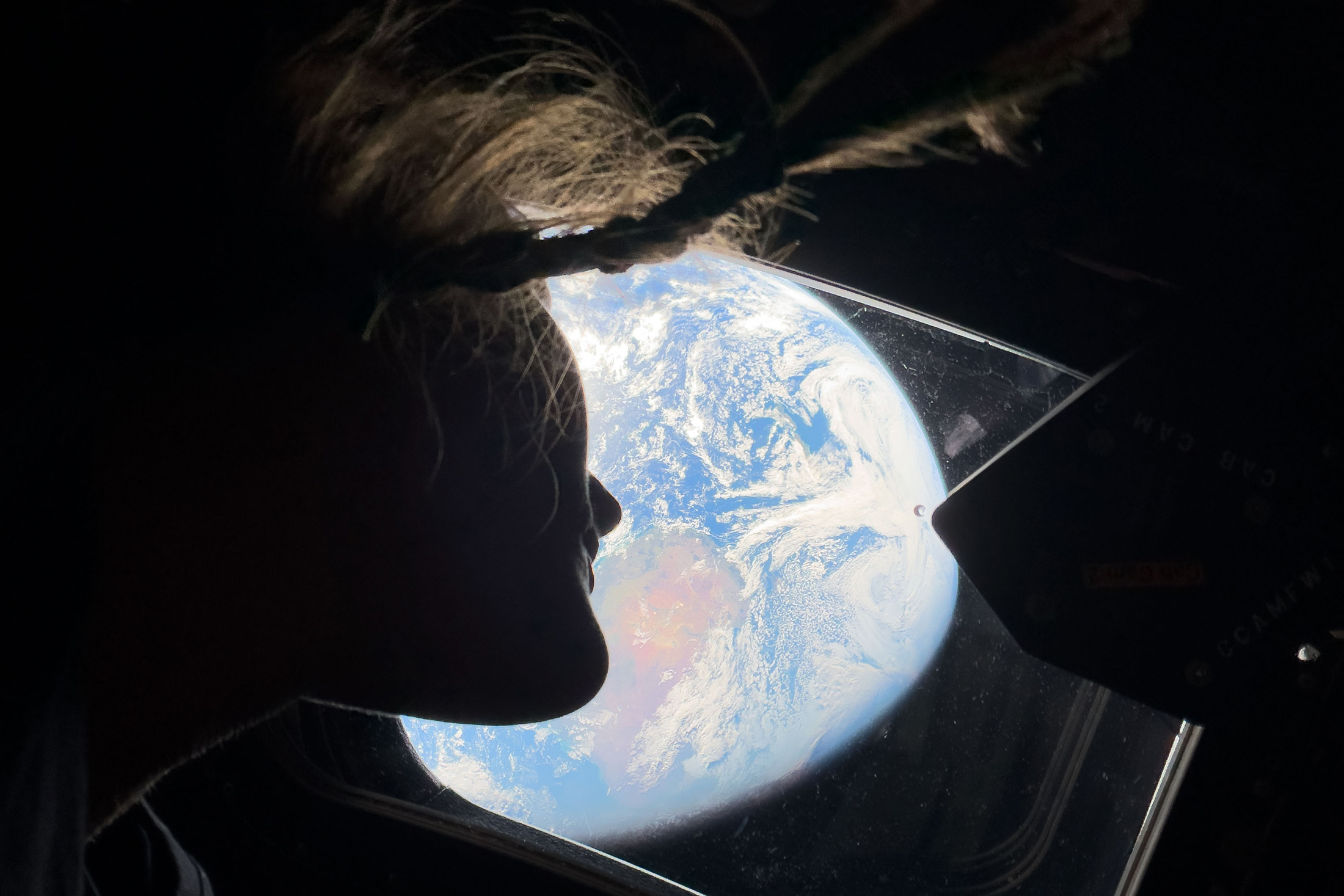 NASA astronaut and Artemis II mission specialist Christina Koch peers out of one of the Orion spacecraft's main cabin windows, looking back at Earth, as the crew travels towards the Moon on April 4, 2026 Source: NASA