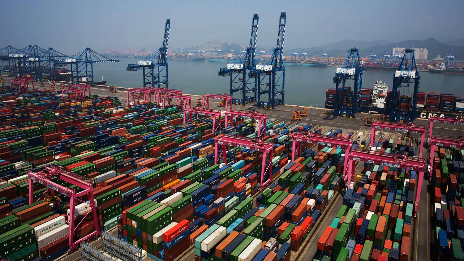 Shipping containers sit stacked among gantry cranes in this aerial photograph taken above the BNCT Co. container terminal at Busan New Port in Busan, South Korea, on Thursday, July 30, 2015. South Korea is scheduled to release trade figures on Aug. 1.
