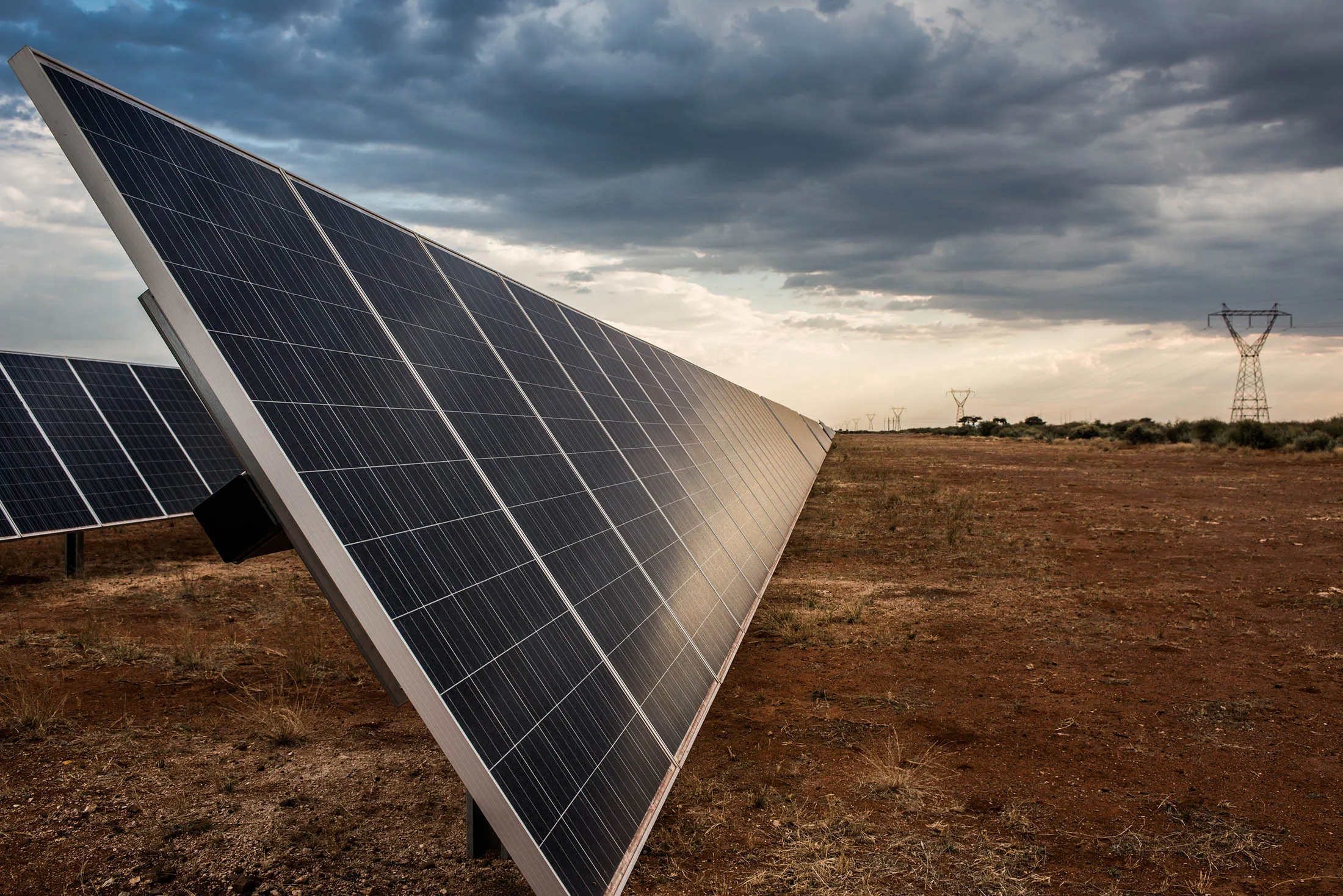 Photovoltaic panels stand near electricity pylons in the Sishen solar park in Kathu, Northern Cape, South Africa.

