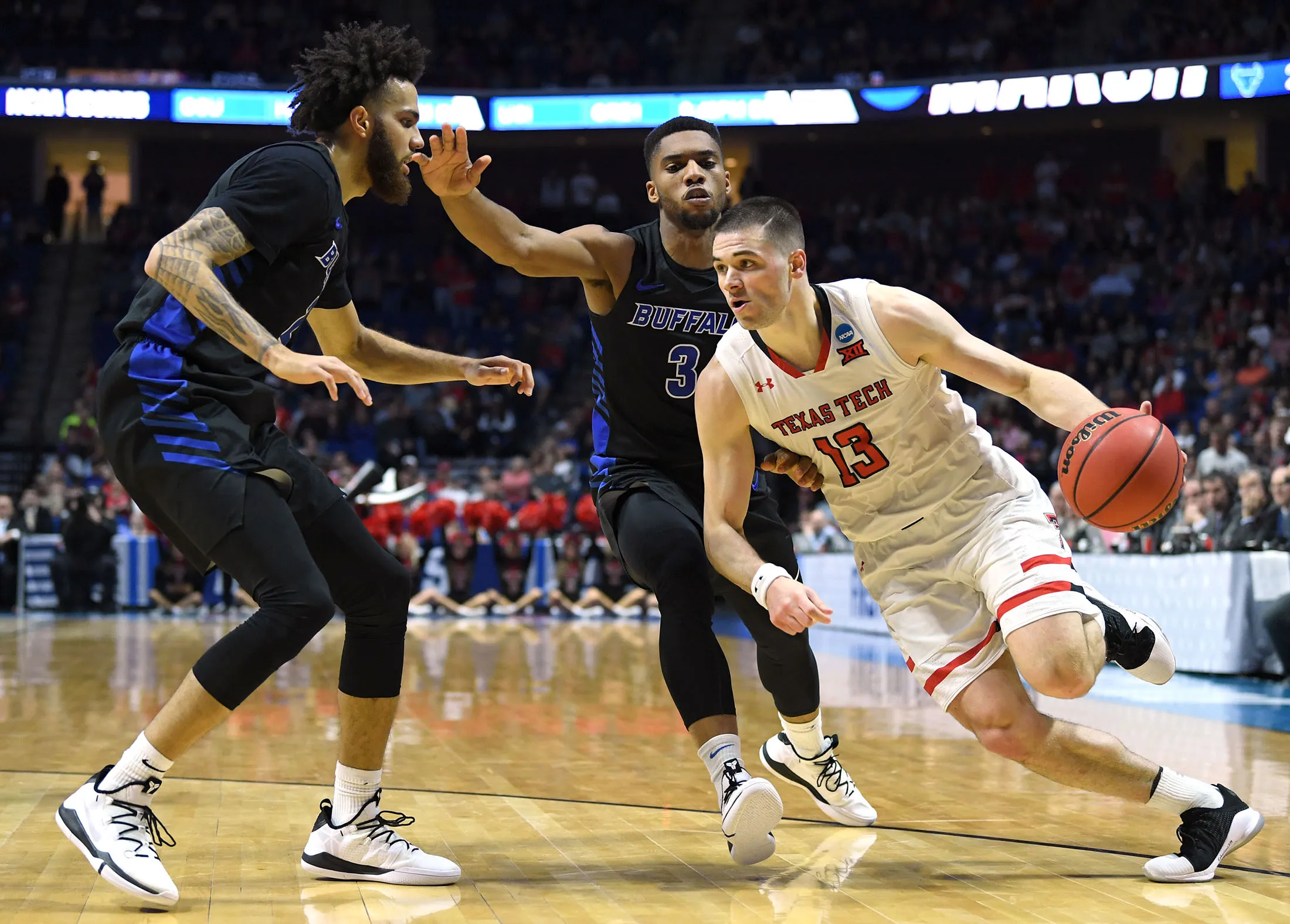 Matt Mooney of the Texas Tech Red Raiders drives past Jeremy Harris and Jayvon Graves of the Buffalo Bulls during the first half of their second round game on March 24.