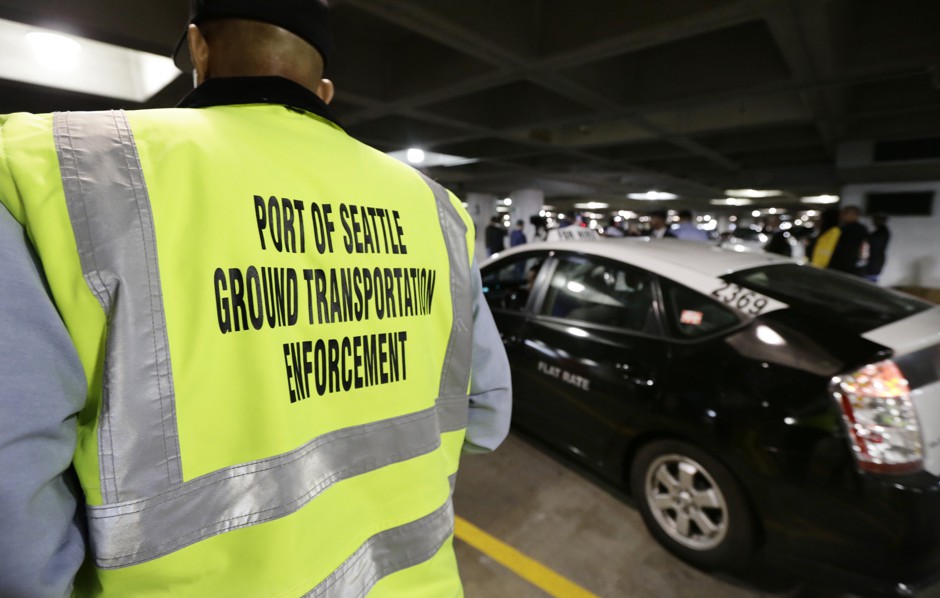A transportation enforcement worker watches ride-hailing vehicles pull into their spaces at Seattle-Tacoma International Airport on March 31, 2016, the first day they could legally pick up and drop off customers there.