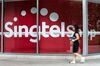 A woman walks past the Singapore Telecommunications Ltd. (SingTel) logo displayed at the company's head office building in Singapore, on Thursday, Aug. 13, 2015. Currency moves have had a "significant" impact on the SingTel's earnings, Chief Executive Officer Chua Sock Koong said in a Bloomberg Television interview.