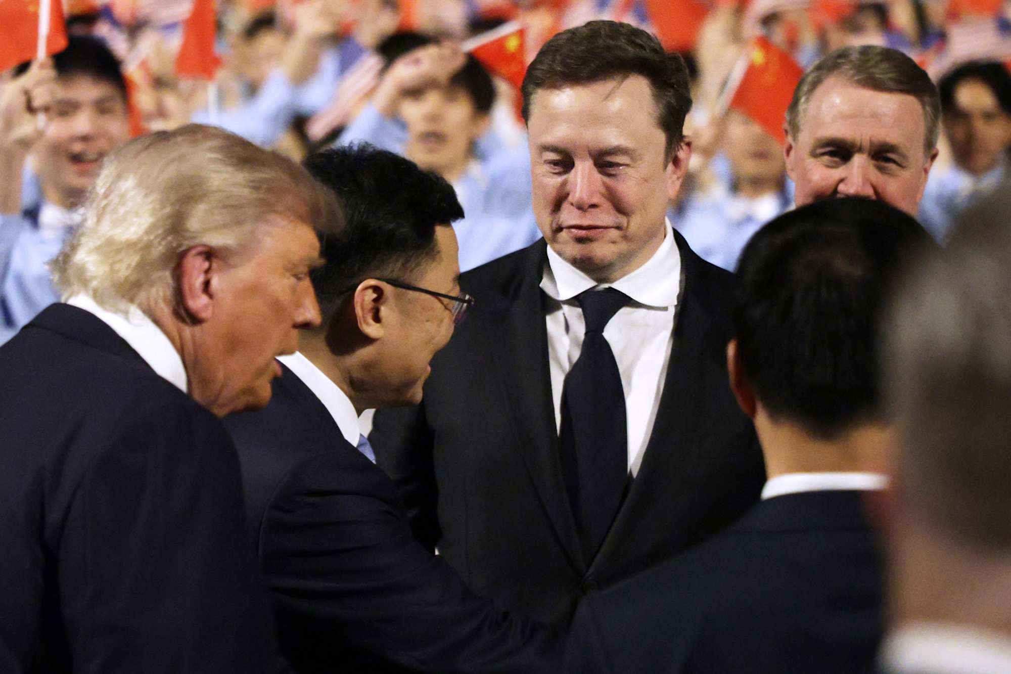 SpaceX CEO Elon Musk follows U.S. President Donald Trump on the red carpet upon arrival at Beijing Capital International Airport on May 13, 2026 in Beijing, China. President Trump is meeting with President Xi Jinping in Beijing to address the Iran conflict, trade imbalances, and the Taiwan situation while establishing new bilateral boards for economic and AI oversight. Photographer: Alex Wong/Getty Images
