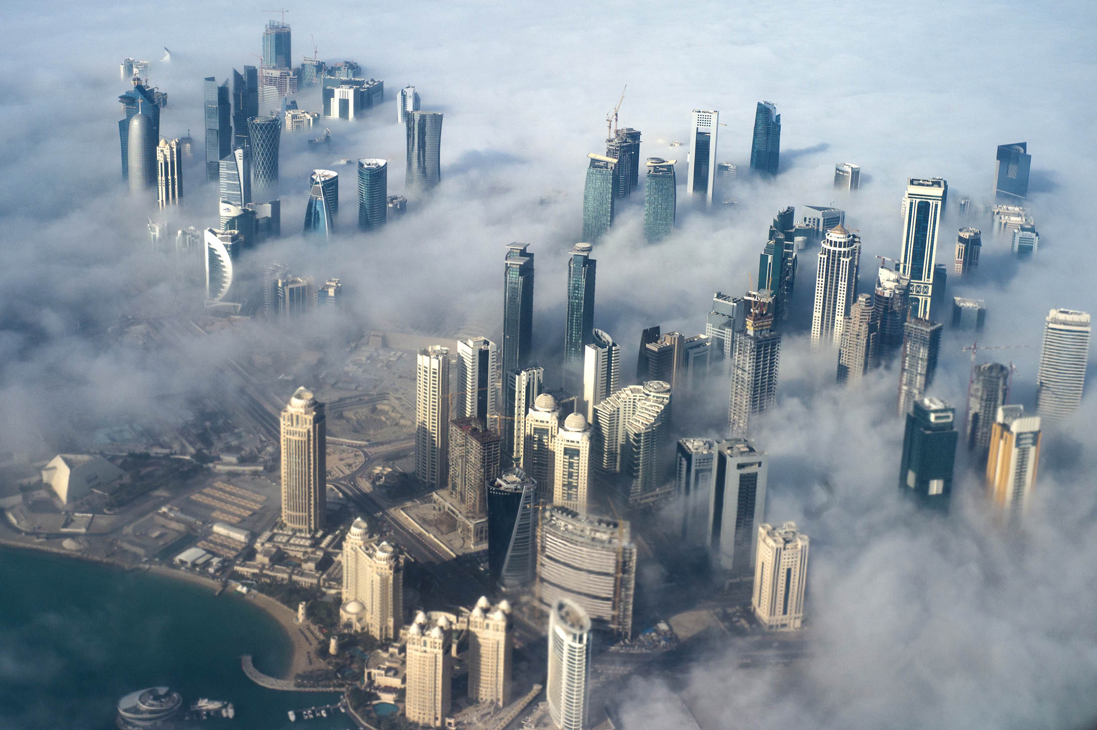 epa06011227 (FILE) - An aerial view of high-rise buildings emerging through fog covering the skyline of Doha, as the sun rises over the city, in Doha, Qatar, 15 February 2014 (reissued 05 June 2017). According to media reports, Egypt, Saudi Arabia, Bahrain and the United Arab Emirates cut off diplomatic ties with Qatar on 05 June 2017, accusing Qatar of supporting terrorism. EPA/YOAN VALAT
