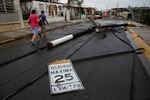 People walk next to fallen electric poles and traffic signs in Salinas, Puerto Rico, after the area was hit by Hurricane Maria.