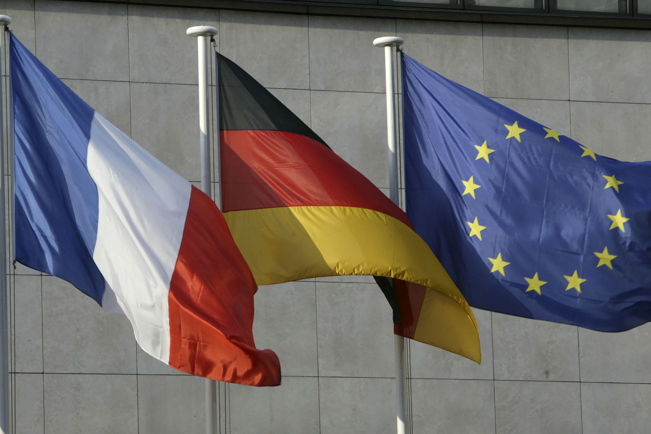 The French, left, German, and European flag, right, fly outside the French-German Economical and Financial Meeting in Paris, France, Monday, January 24, 2005.
