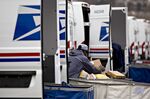 A letter carrier prepares a vehicle for deliveries at the United States Postal Service.