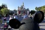 A patron wearing a Mickey Mouse hat walks in front of Sleeping Beauty Castle at Walt Disney Co.'s Disneyland amusement park in Anaheim, California, U.S..