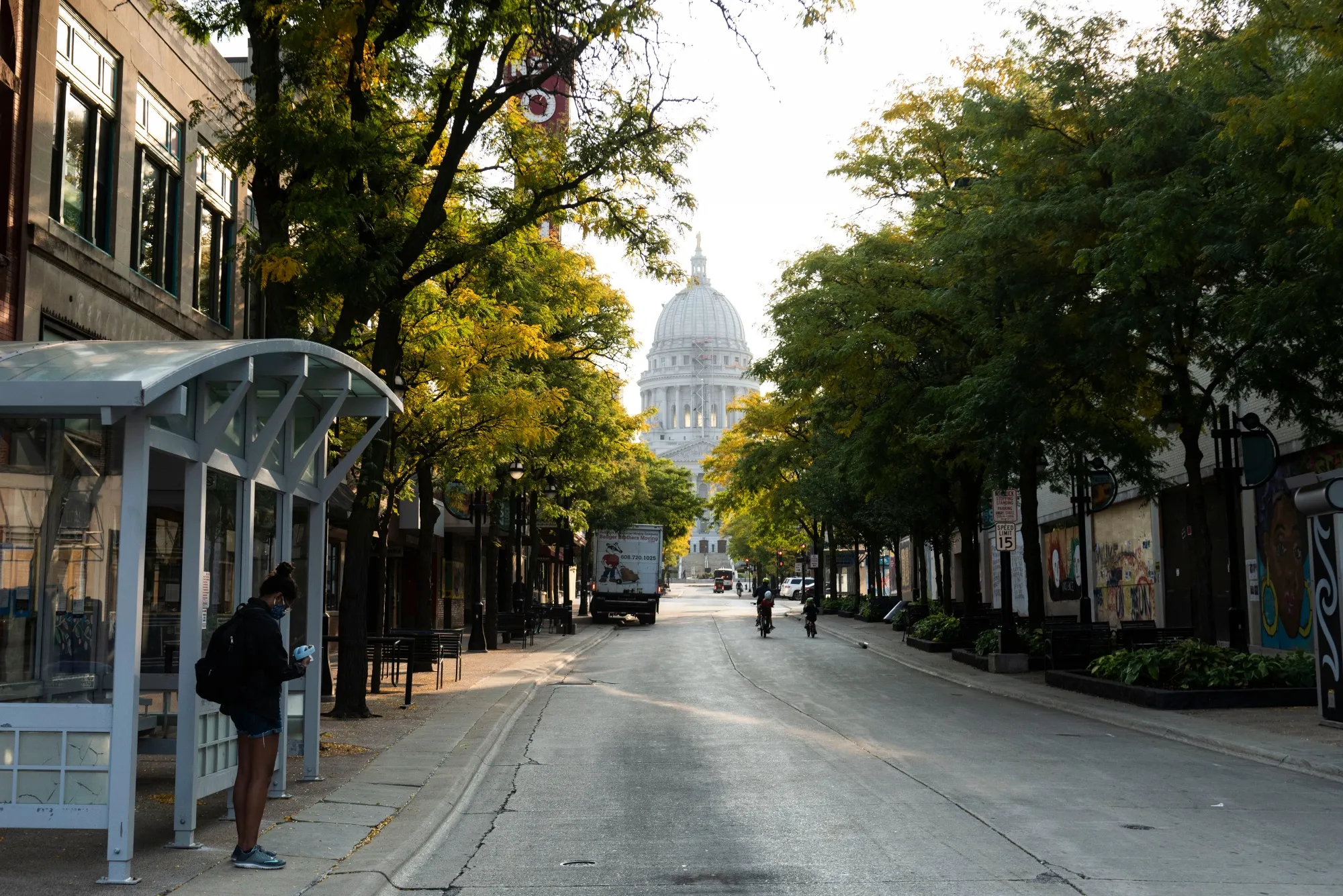 A commuter waits at a bus stop near the Wisconsin State Capitol building in Madison, Wisconsin on Sept. 23. Wisconsin had one of the worst outbreaks in the U.S. per-capita in the past week.