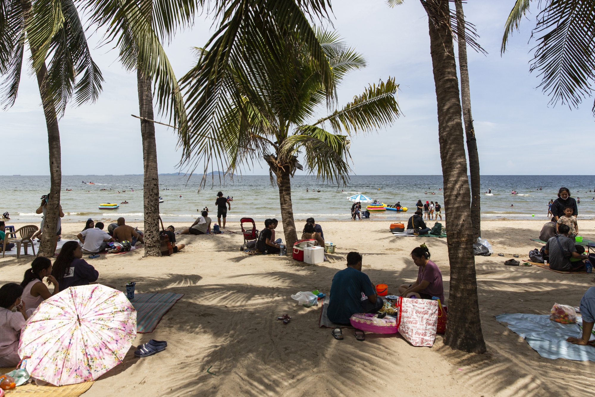 Visitors sit in groups as they relax on the beach and in the sea at Bangsaen Beach in Chonburi, Thailand, on June 14.
