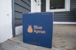 A Blue Apron box sits on the porch of a house.