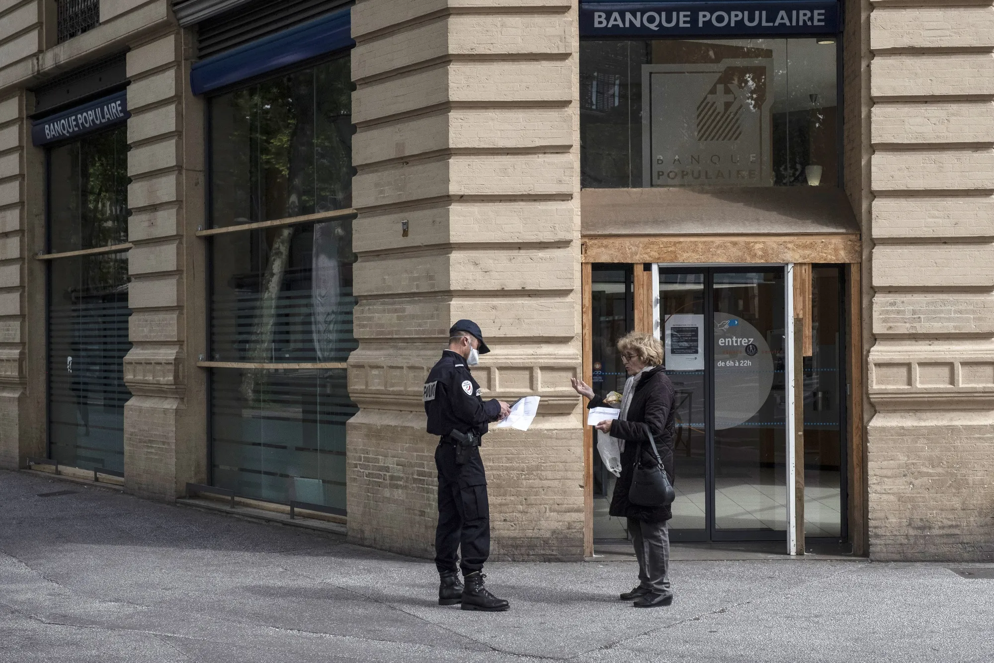 A police officer checks a pedestrian's paperwork outside a Banque Populaire bank branch during coronavirus lockdown in Toulouse, on April 27.
