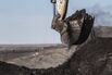 An excavator scoops up coal in an open pit