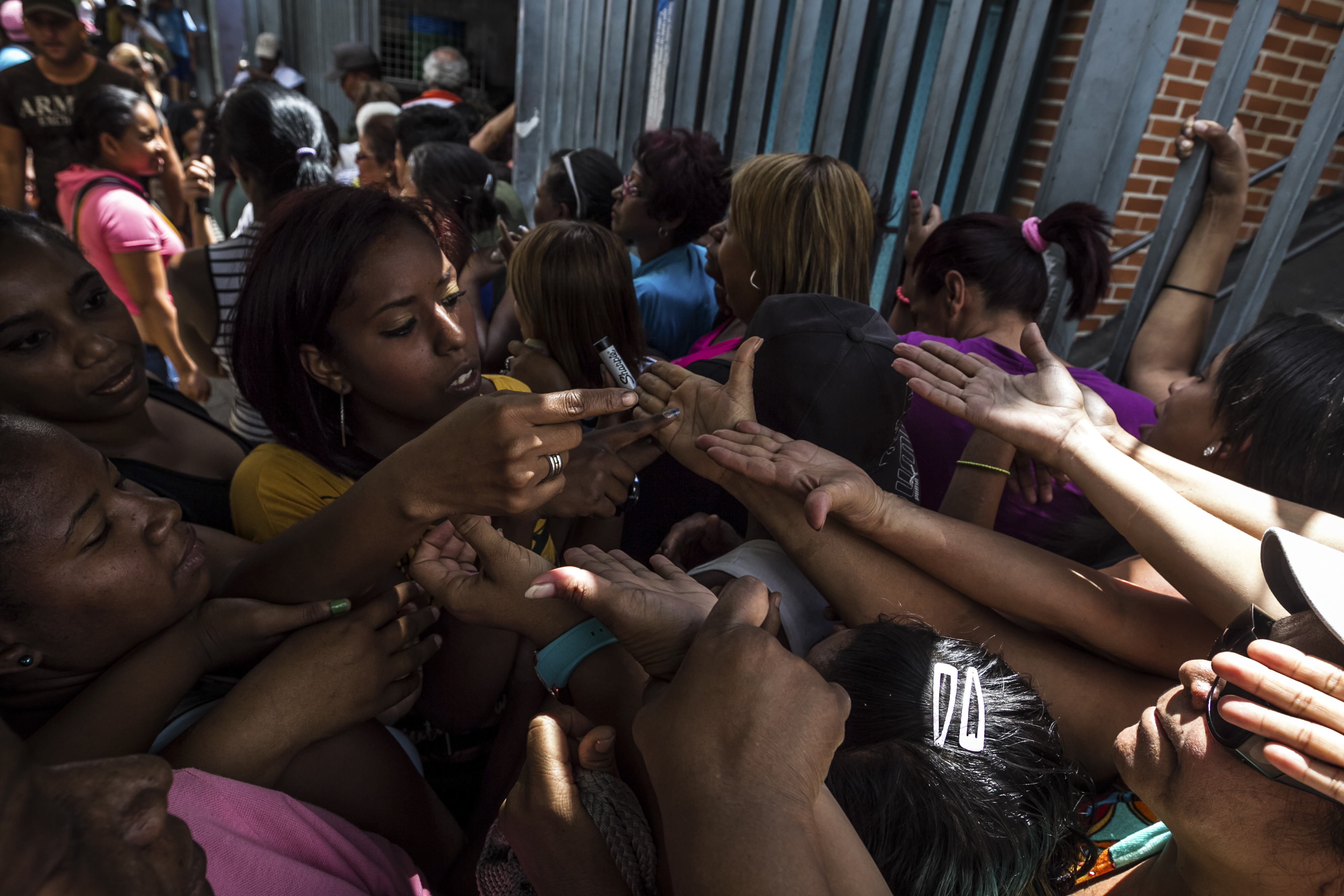 Shoppers get their hand marked with a number to save their place in line to enter a private-sector grocery store in Caracas, Venezuela, on Saturday, Feb. 21, 2015.
