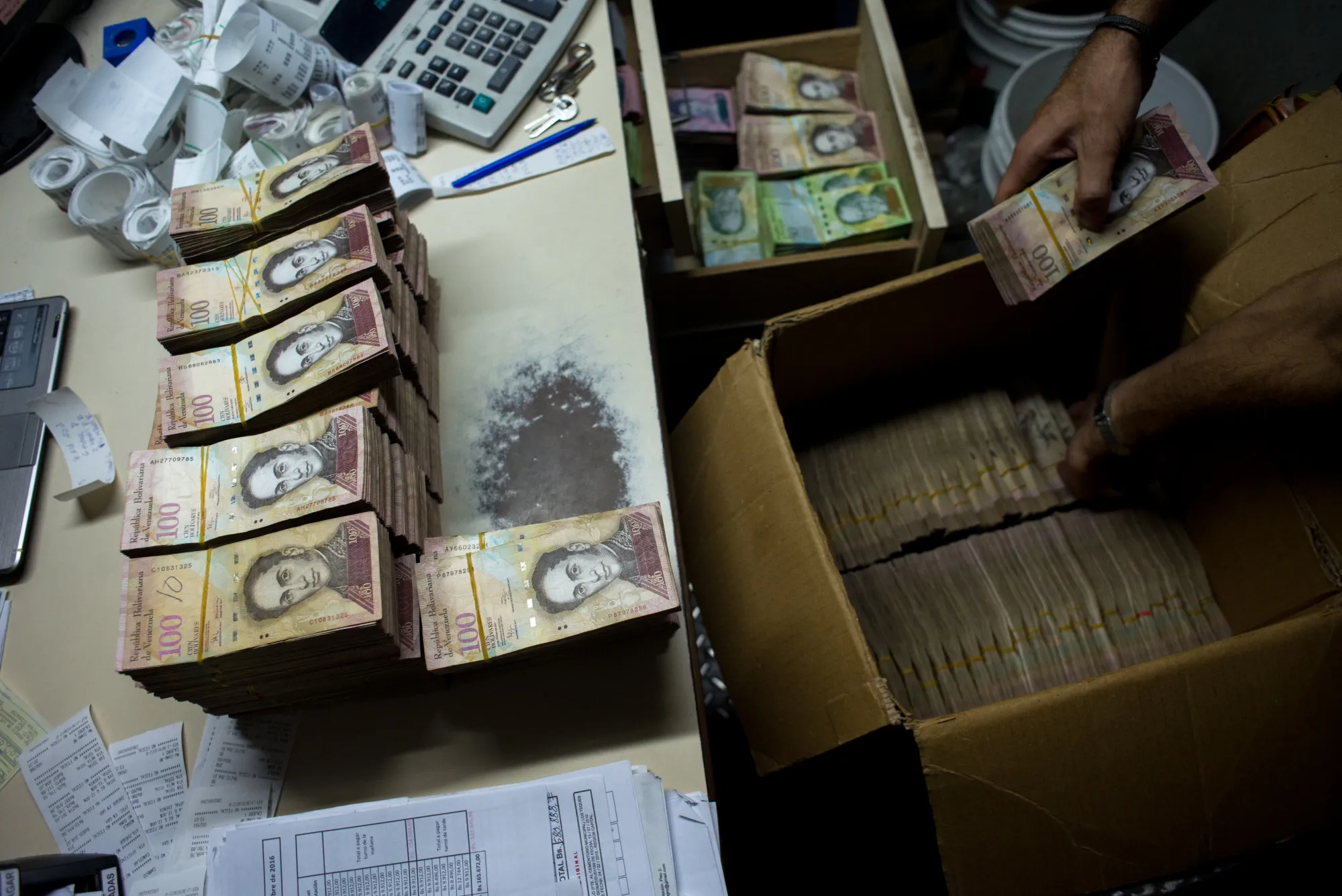 A manager places the banknotes received from customers during the day into a cardboard box in Caracas.