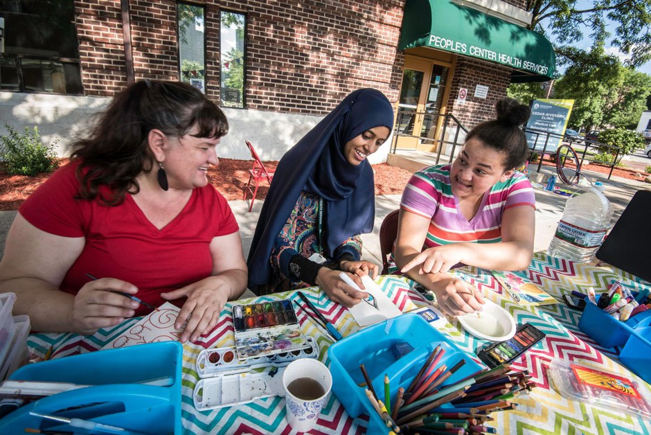 Artist Soozin Hirschmugl (left) paints with visitors on the lawn of the People's Center Health Services in Minneapolis. 