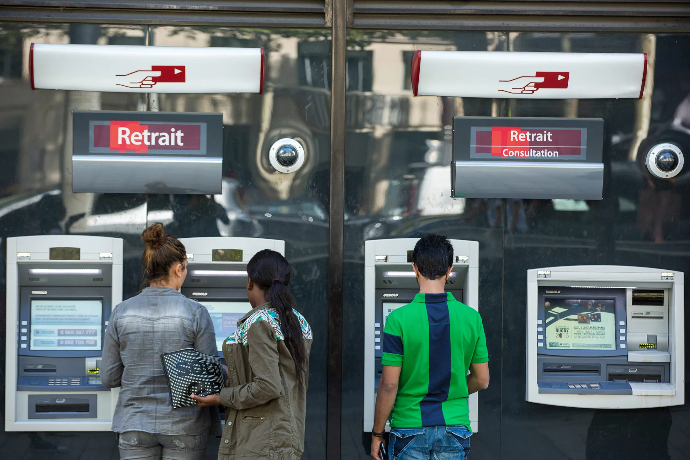 Customers use automated teller machines (ATM) outside a branch of Societe Generale SA in Paris.
