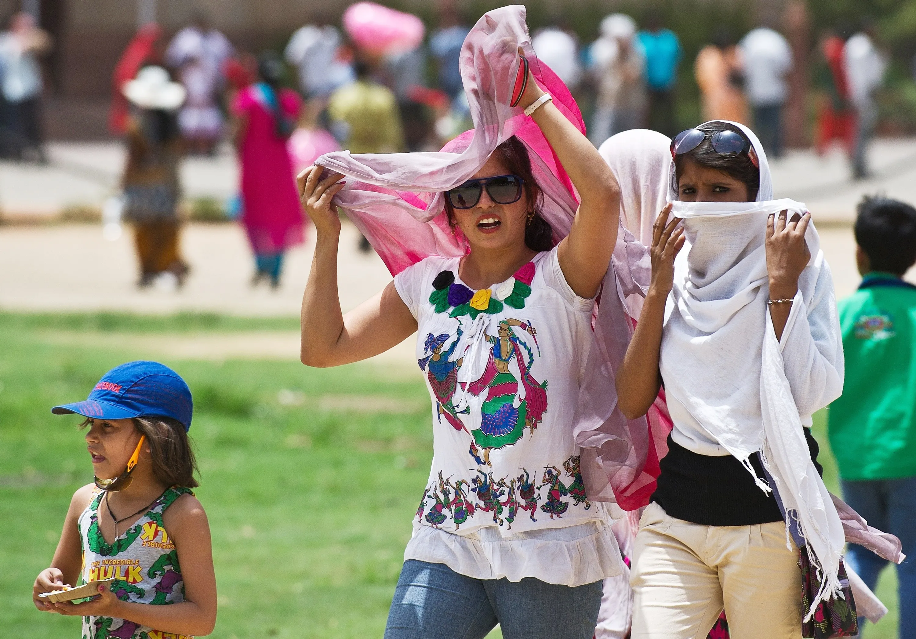 Visitors at the India Gate monument cover themselves to protect themselves from the sun during a heatwave in New Delhi on June 10, 2014.