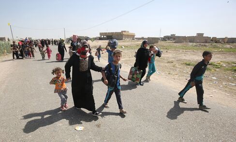 Iraqis walk towards a military point as they flee the violence in their village of Saqlawiyah, north west of Fallujah, on June 3, 2016.