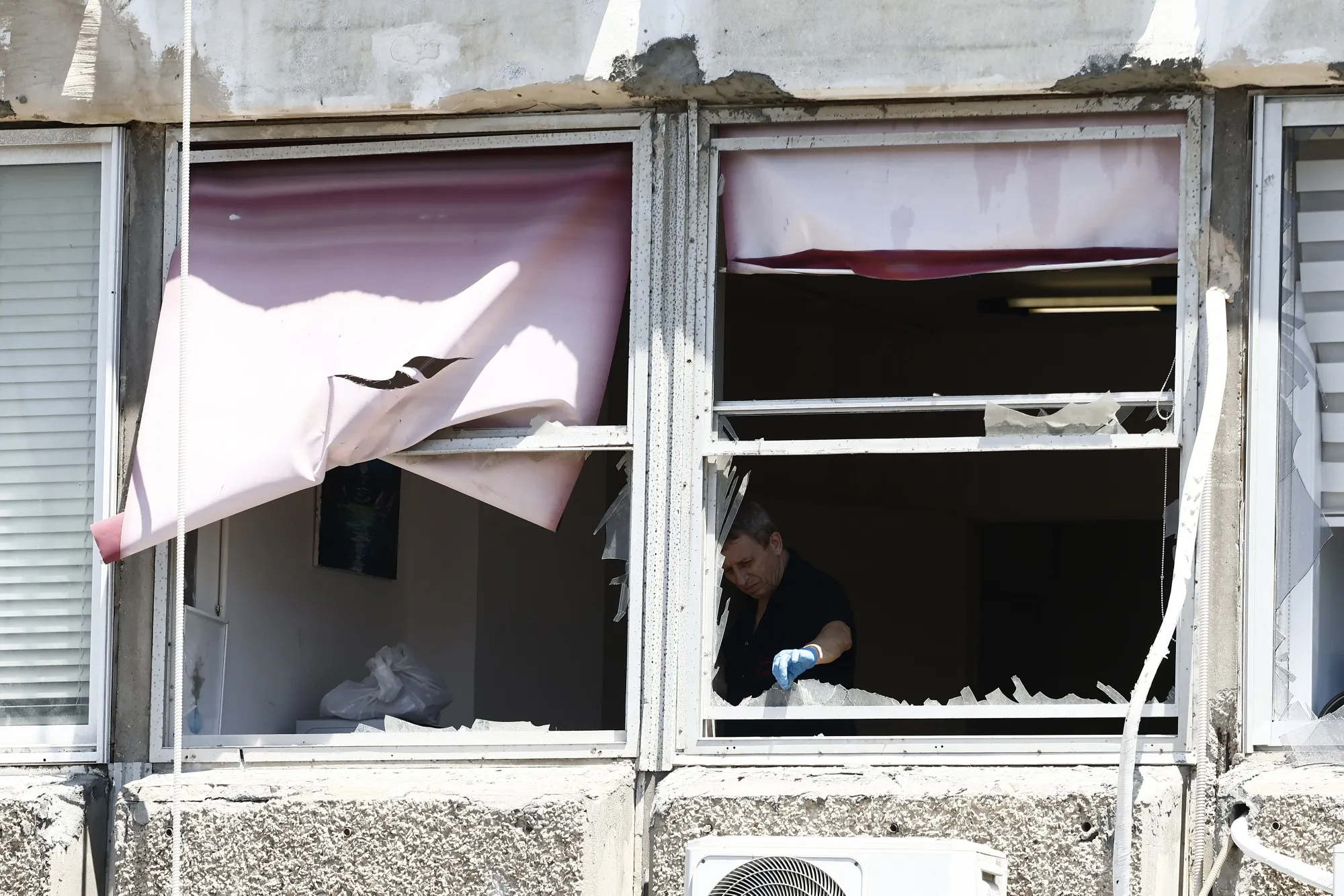 An investigator removes shards of glass from an apartment window following a&nbsp;Houthi drone&nbsp;strike in Tel Aviv, Israel, on&nbsp;July 19.