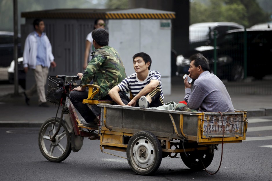 Migrant workers ride on a motorized tricycle through a crossing in Beijing.
