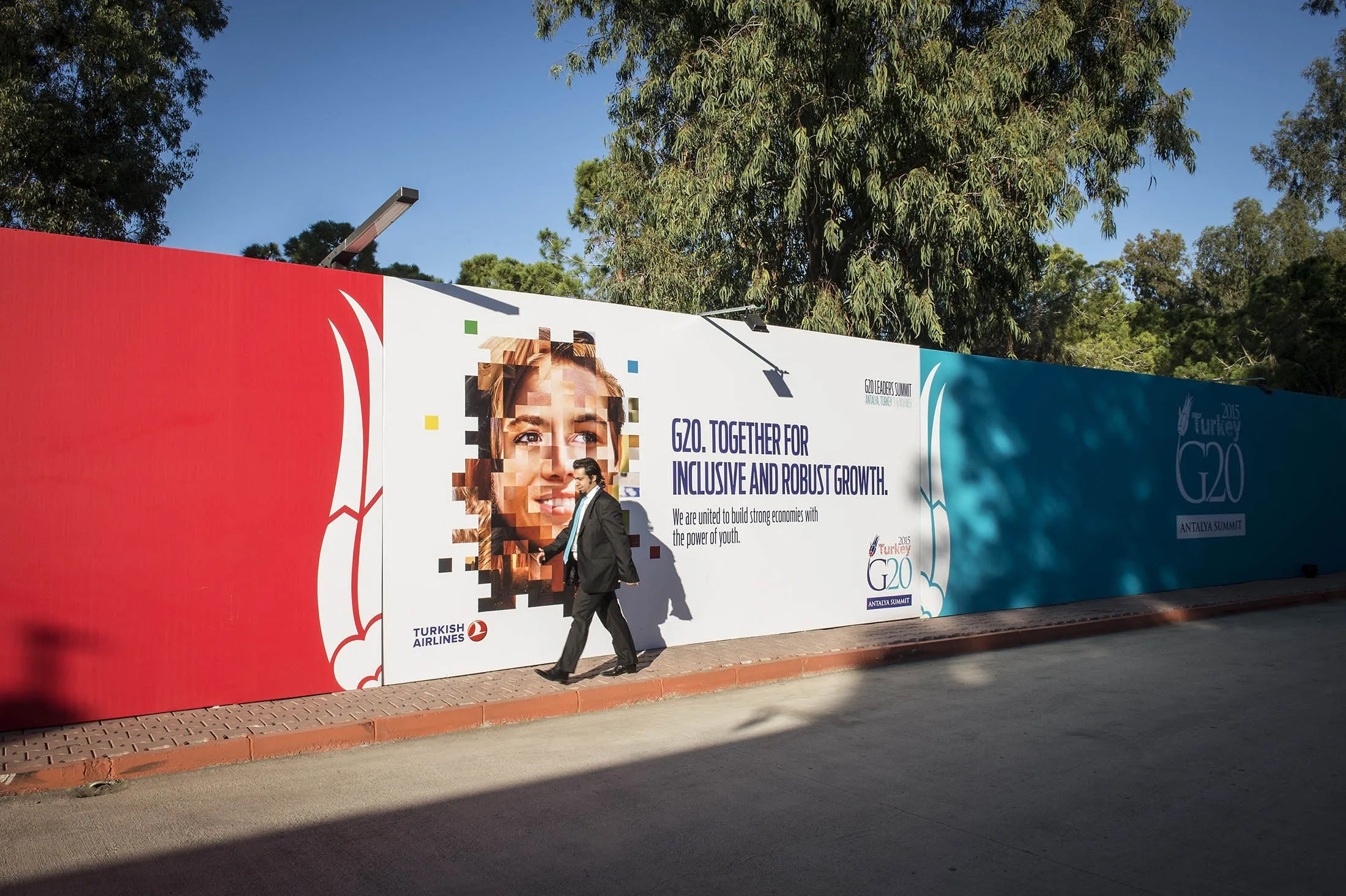 A person walks past a banner outside the press center as final preparations are being done for the upcoming G-20 Leaders Summit in Antalya, Turkey.
