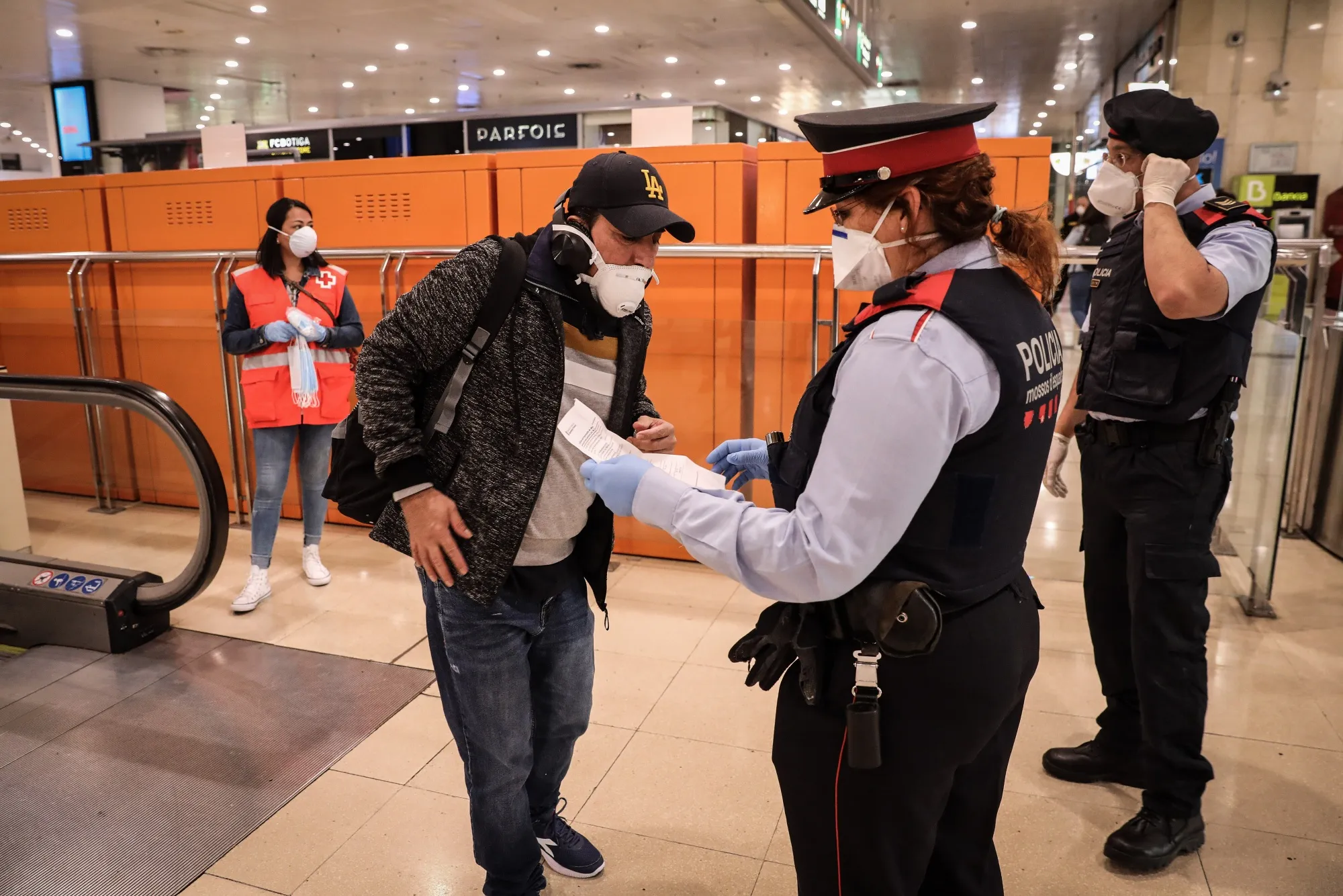 A member of the Mossos d'Esquadra police force wearing a protective face mask checks the papers of a commuter during a patrol inside Barcelona Sants railway station in Barcelona, on April 14.