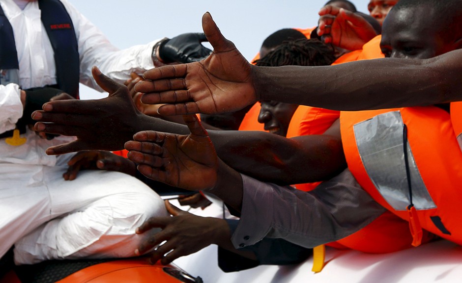 Migrants reach out to grab hold of Migrant Offshore Aid Station rescuers off the coast of Libya, August 3, 2015. 
